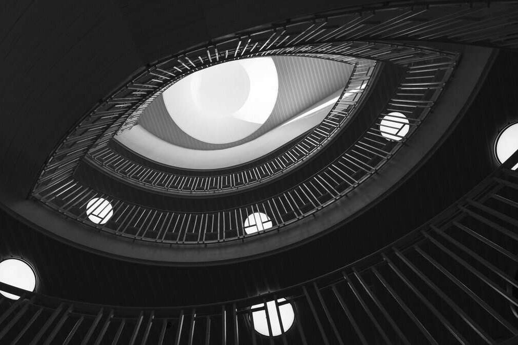 Aspirational spiral staircase with modern design and circular lighting, viewed from below, showcasing sleek architecture and creative interior design.